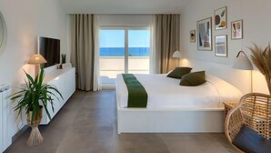 Una habitación de hotel moderna con una cama grande, televisión, escritorio y vista al mar.