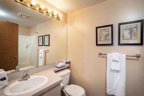 Une salle de bain avec un lavabo, des toilettes et un porte-serviettes. Des tableaux encadrés ornent le mur.