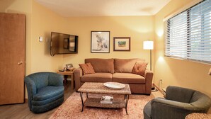 A living room with a sofa, two armchairs, a coffee table, a TV, and framed pictures on the wall. - Cozy condo w/great location by Flathead Lake - Cozy Marina Cay Getaway (Bigfork)