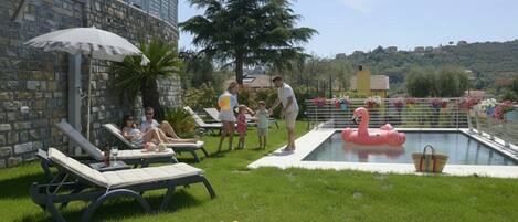 A poolside area with lounge chairs, a swimming pool, and a decorative flamingo float.