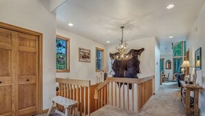 A wooden staircase with a bench, a chandelier, and a large animal hide wall.