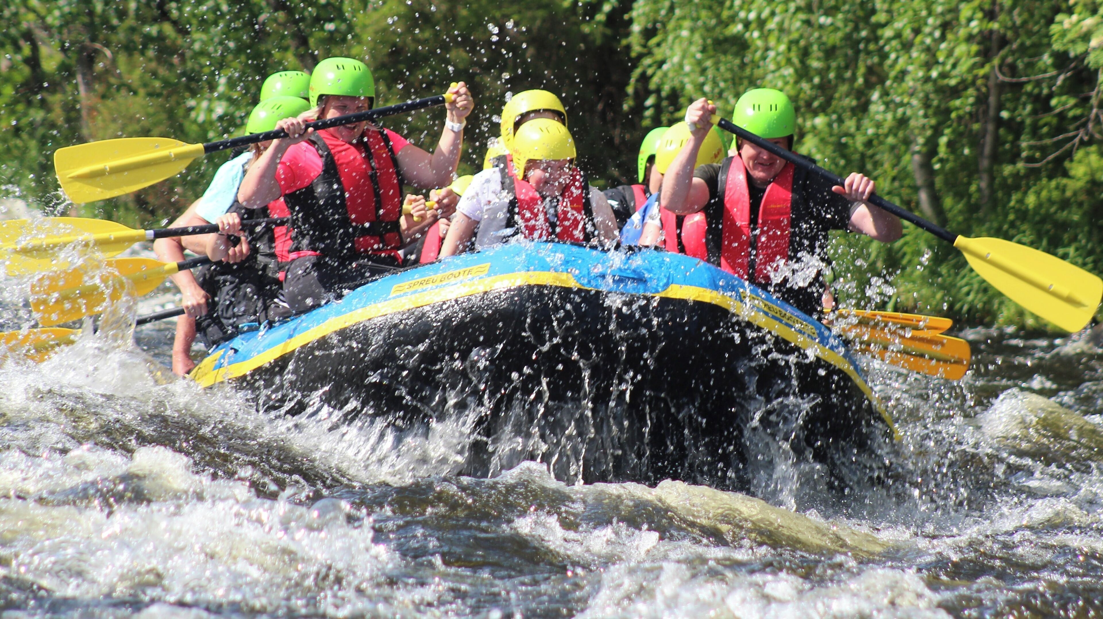Een groep mensen in een raft die door torenende watervallen peddelt.