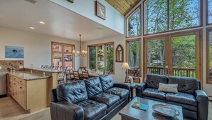 A spacious living area with a kitchen, dining table, and two leather sofas.