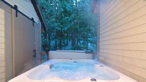 Ein Whirlpool mit Bedienfeld, umgeben von Holzwänden und Blick auf einen Wald.