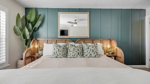 A bedroom with a bed, a ceiling fan, a large mirror, and a potted plant. - NEW Updated 2/2, Beachfront with a private balcony, Atlantic Ocean views, and a heated pool (New Smyrna Beach)