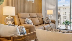 A modern living room with a leather sofa, two lamps, and a neon sign reading "Seaside Holiday". - NEW Updated 2/2, Beachfront with a private balcony, Atlantic Ocean views, and a heated pool (New Smyrna Beach)