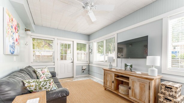 A living room with a grey couch, a wooden cabinet, a TV, and a ceiling fan. - Yellow Cottage in Lake Chelan (Chelan)