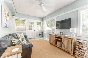A living room with a grey couch, a wooden cabinet, a TV, and a ceiling fan. - Yellow Cottage in Lake Chelan (Chelan)