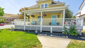 A two-story house with a porch, a mailbox, and a street view. - Yellow Cottage in Lake Chelan (Chelan)
