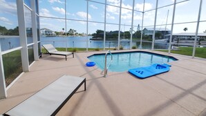 A pool area with a clear view of the lake, lounge chairs, and a blue floating platform. - Seascape - WHOLE HOUSE 360 water views, pool, gulf (Hernando Beach)