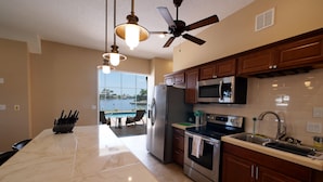 A modern kitchen with a large island, stainless steel appliances, and a view to the outside. - Seascape - WHOLE HOUSE 360 water views, pool, gulf (Hernando Beach)