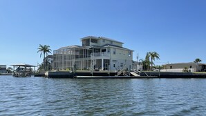 A waterfront property with a large house, a dock, and a boat. - Seascape - WHOLE HOUSE 360 water views, pool, gulf (Hernando Beach)