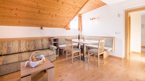 Une pièce chaleureuse avec un plafond en bois, un canapé, une table à manger avec des chaises et une petite table sur laquelle se trouve un panier.