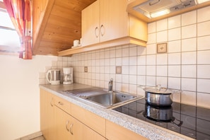 Cucina con pensili in legno, lavello in acciaio inossidabile, fornello e macchina da caffè.