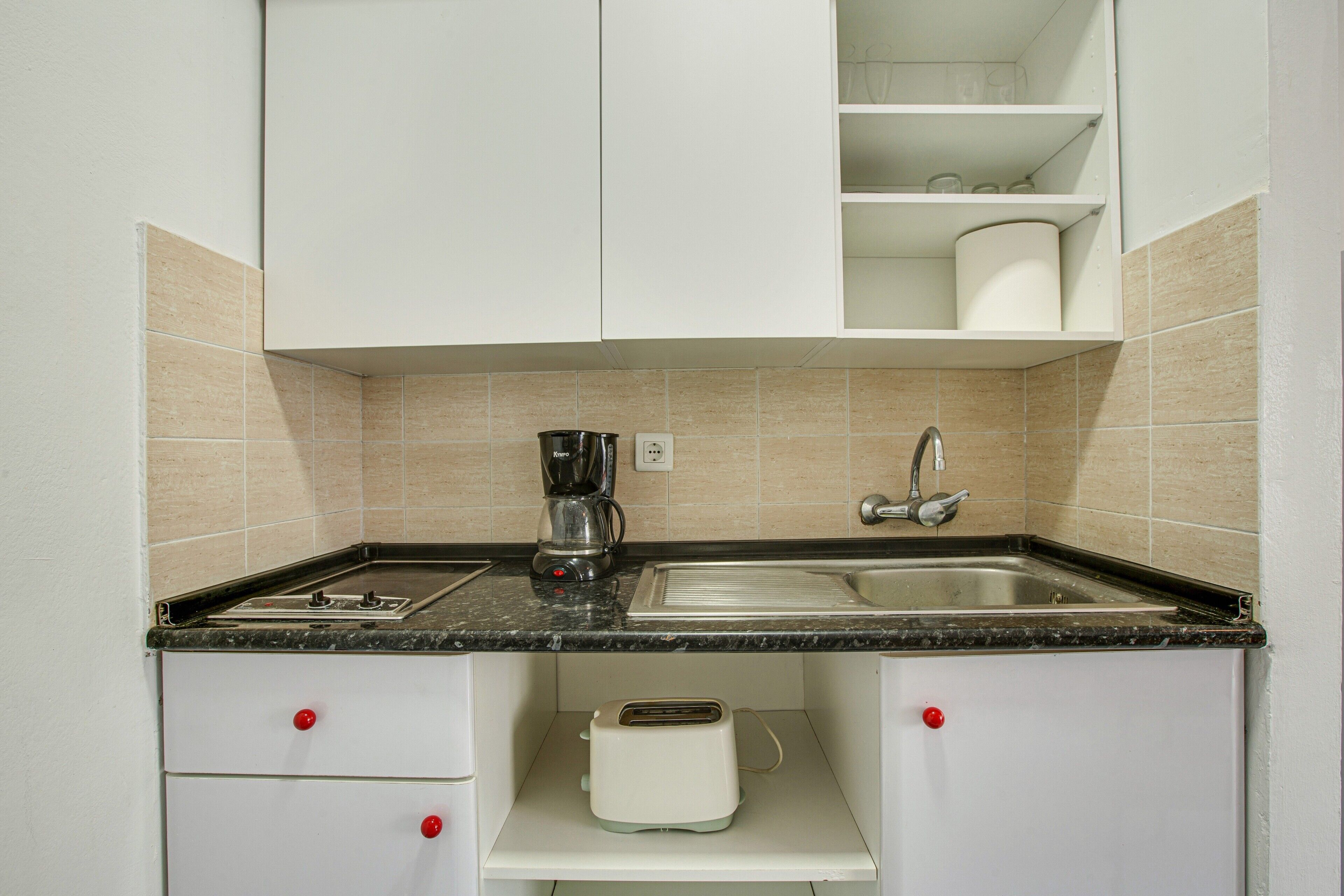 Una cocina con un lavamanos, una cafetera y un tostador.