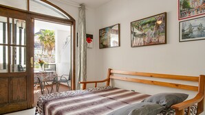 A bedroom with a wooden bed, a view of the outdoors, and a table with chairs.