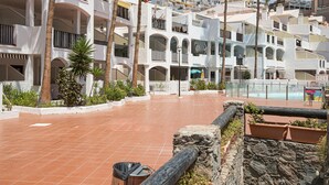 A multi-story hotel with balconies, a swimming pool, and terracotta-tiled courtyard.