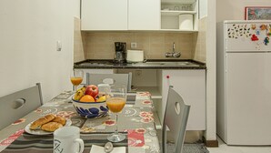A kitchen with a dining table set for breakfast, including croissants, fruit, and juice.