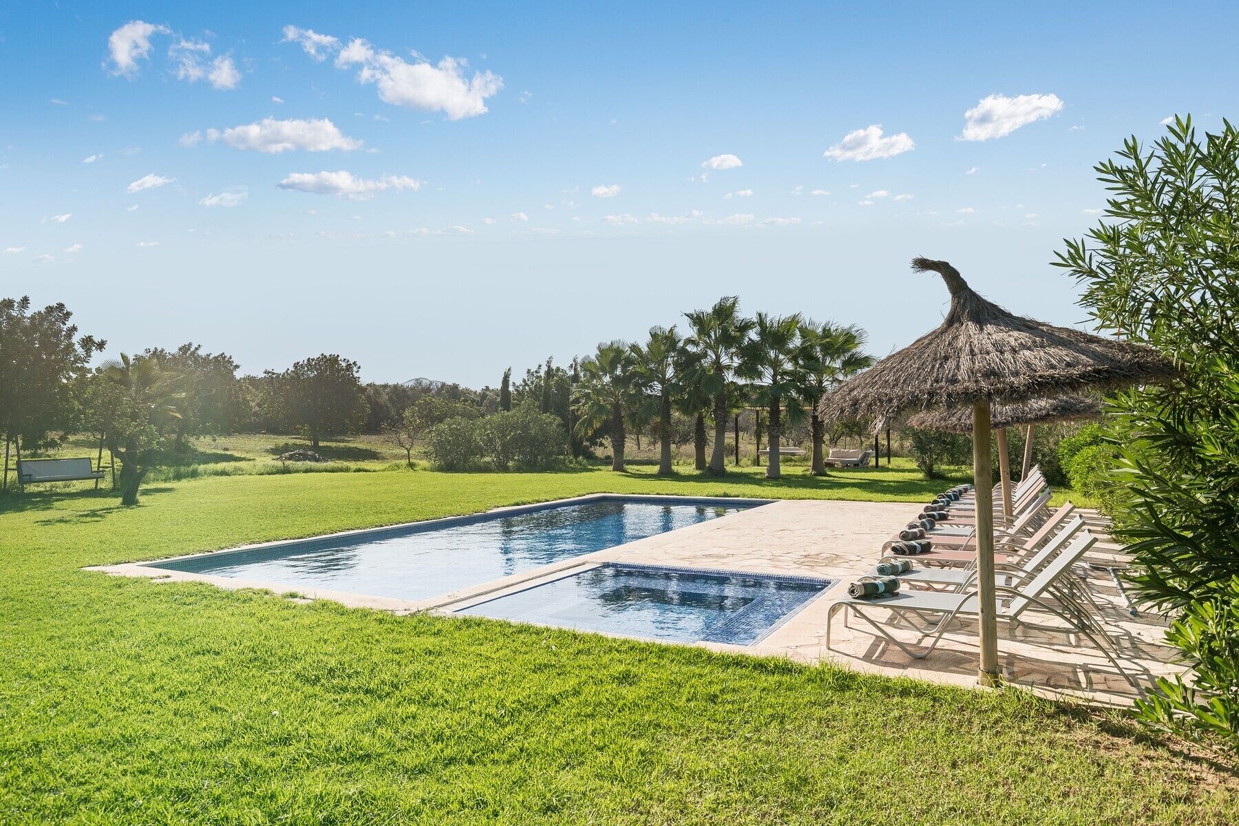Ein Swimmingpool mit einer strohgedeckten Struktur und Liegestühlen.