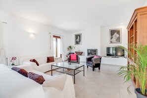 Un salon moderne avec un canapé, un fauteuil, une table basse, un téléviseur et une plante en pot.