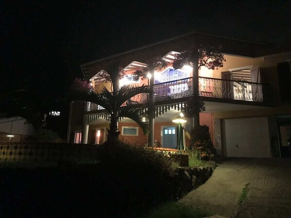 A two-story house with a balcony, a garage, and a well-lit entrance.