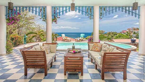 A covered outdoor seating area with a pool, wooden furniture, and a view of the ocean. - Villa Sol y Sombra the Cuban spirit (Schoelcher)