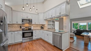 A modern kitchen with white cabinetry, stainless steel appliances, and a wooden floor. - Margaritaville Luxurious Lakeview Living (Osage Beach)