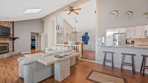 A spacious living area with a fireplace, a dining area, and a kitchen with bar stools. - Margaritaville Luxurious Lakeview Living (Osage Beach)