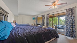 A bedroom with a large bed, a ceiling fan, and a view of the outdoors through a sliding glass door. - Margaritaville Luxurious Lakeview Living (Osage Beach)