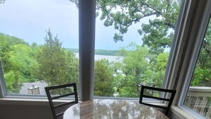 A round table with four chairs, a large window with a view of trees and a body of water. - Margaritaville Luxurious Lakeview Living (Osage Beach)