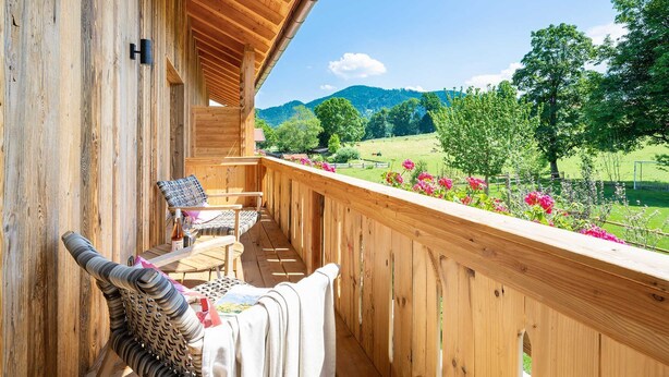 Un balcón de madera con vistas a un paisaje verde y montañas.