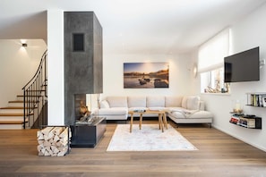 A modern living room with a fireplace, a sofa set, a coffee table, and a television mounted on the wall.