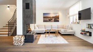Una sala de estar moderna con chimenea, un juego de sofá, una mesa de centro y un televisor montado en la pared.
