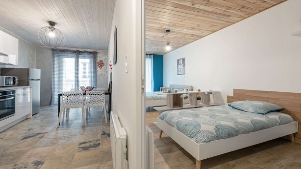 A modern apartment with a kitchen, dining area, and a bedroom.