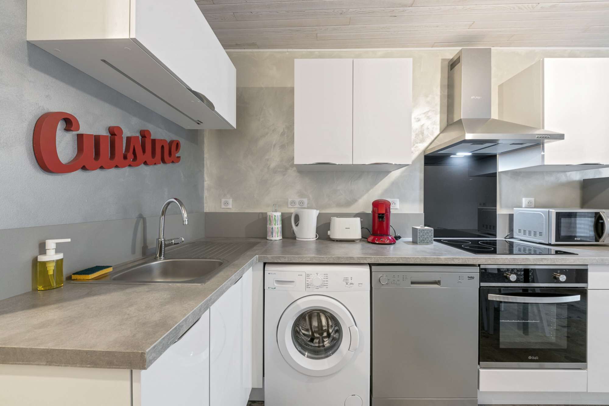 A modern kitchen with a dishwasher, washing machine, microwave, and a coffee maker.