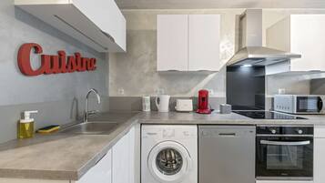 A modern kitchen with a dishwasher, washing machine, microwave, and a coffee maker.