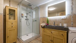 Ett modernt badrum med en duschavdelning med glasväggar, träskåp och en inbyggd tvättmaskin.