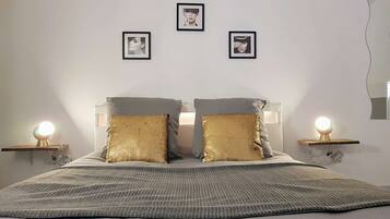 Een keurig opgemaakt slaapkamer met een bed, twee nachtkastjes met lampen, en drie ingelijste foto's aan de muur.