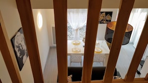 A dining area with a white table set for four, a patterned chair, and a decorative wall piece. - ★ Bright ★ Quiet ★ City centre ★ Easy Parking ★ WIFI ★ (Le Puy en Velay)