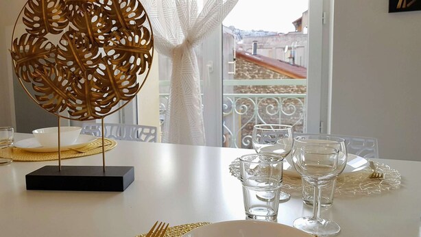 A dining table with a decorative centerpiece, clear glassware, and a view of a balcony with a railing. - ★ Bright ★ Quiet ★ City centre ★ Easy Parking ★ WIFI ★ (Le Puy en Velay)