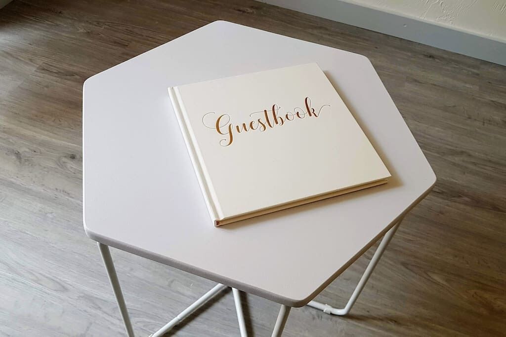 A white, hexagonal table with a guestbook on top.