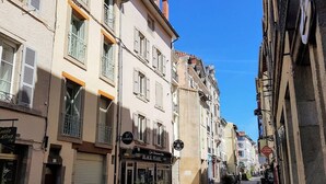 Una calle estrecha con edificios que tienen tiendas en la planta baja, incluyendo un bar llamado 'The Black Pearl'.