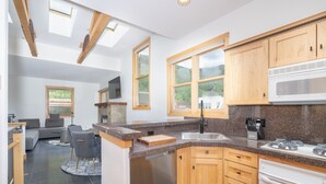 Una cocina moderna con electrodomésticos integrados, armarios de madera y grandes ventanales que ofrecen vistas al exterior.