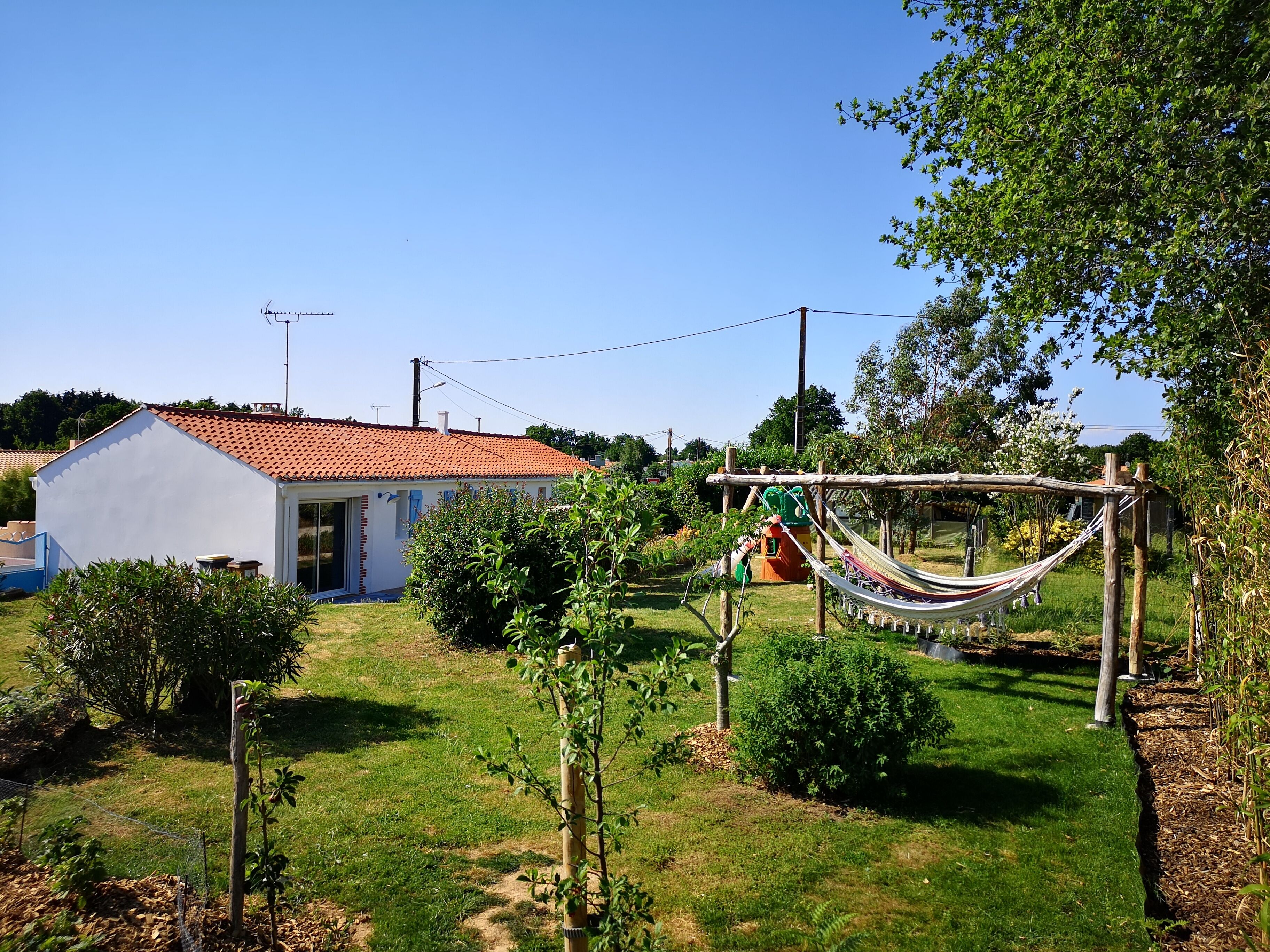 Ein Haus mit rotem Ziegeldach, weißem Anstrich und einem Garten mit einer Hängematte.