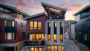 Una casa moderna de varios pisos, con base de piedra, ventanas grandes y un balcón.