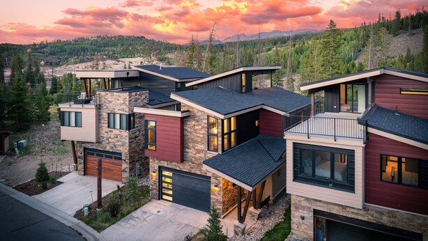Una casa moderna de varios pisos con fachada de piedra, ventanas amplias y garaje.