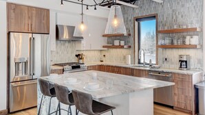 Una cocina moderna con una isla central, electrodomésticos de acero inoxidable y un amplio ventanal.