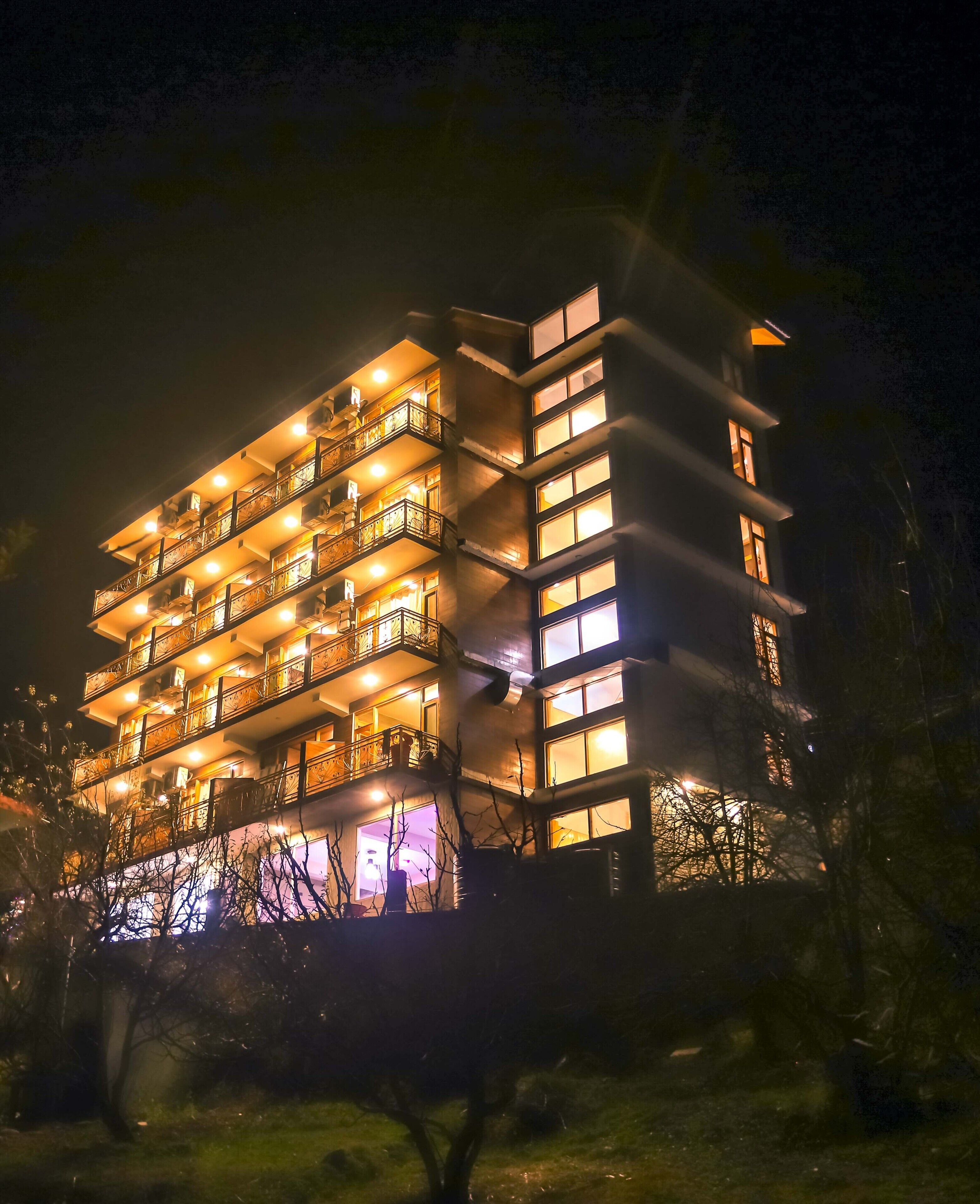 Ein mehrstöckiges Hotel mit Balkonen und beleuchteten Fenstern bei Nacht.