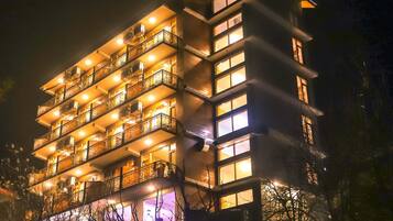 Ein mehrstöckiges Hotel mit Balkonen und beleuchteten Fenstern bei Nacht.
