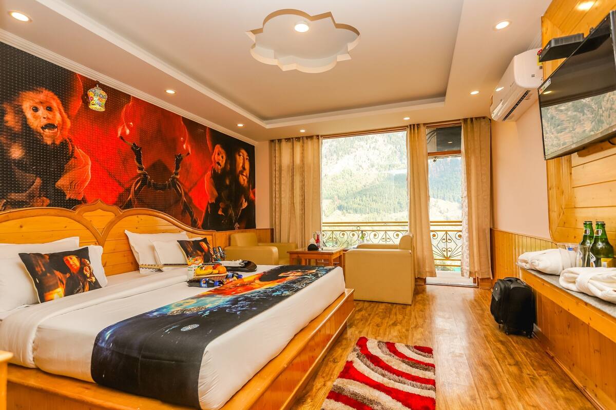 A hotel room with a bed, a TV, a desk with a chair, a window with a view, and a balcony.